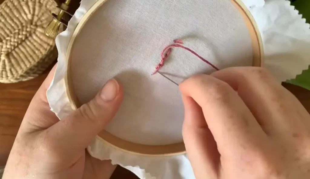 Thread the floss through the eye of the needle, securing it for stitching.